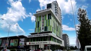 un edificio alto verde y blanco en una calle de la ciudad en Swan Garden Hotel, en Melaka