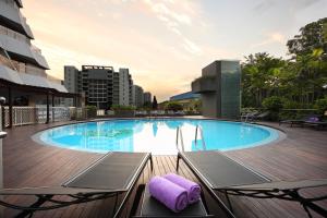 a large swimming pool with two chairs and a purple towel at Village Hotel Katong by Far East Hospitality in Singapore