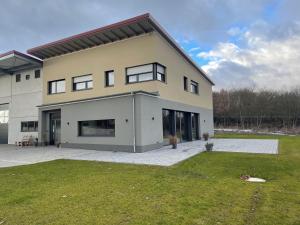 ein großes Haus mit Rasen davor in der Unterkunft Weingut Bugner Meizelhof in Klein-Winternheim