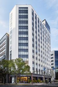 un grand bâtiment blanc avec un magasin devant lui dans l'établissement THE KNOT HIROSHIMA, à Hiroshima