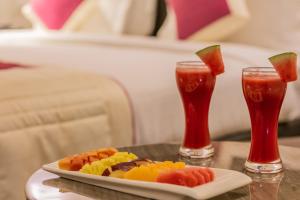 a plate of fruit on a table with two drinks at Best Western Ramachandra in Visakhapatnam