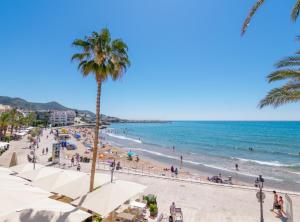 una playa con palmeras y gente en la playa en 1840 Apartments Sitges, en Sitges