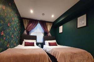 two beds in a room with green walls and a window at Enchanted Hideaway, Bath in Bath