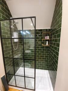 y baño con ducha y paredes de azulejos verdes. en Enchanted Hideaway, Bath, en Bath