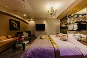 ein Schlafzimmer mit einem großen Bett und einer Couch in der Unterkunft HOTEL MYTH-W -ホテル マイス ダブリュー- adult only in Sakaide