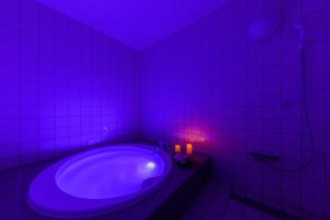 ein Badezimmer mit einer Badewanne mit violettem Licht in der Unterkunft HOTEL MYTH-W -ホテル マイス ダブリュー- adult only in Sakaide