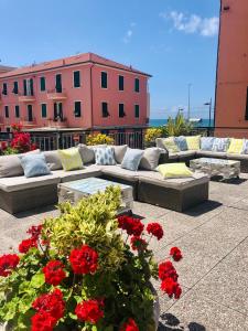 a patio with couches and red flowers on a building at Hotel Doria in Cavi di Lavagna