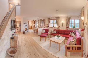 a living room with a red couch and a table at Ferienwohnungen im Rosengarten inkl. Chiemgaukarte in Ruhpolding