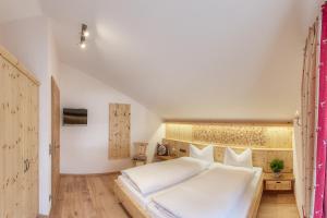 a bedroom with a large white bed and wooden floors at Ferienwohnungen im Rosengarten inkl. Chiemgaukarte in Ruhpolding