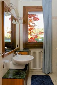 baño con lavabo blanco y ventana en Villa con ampio giardino esterno e piscina condominiale, en Garda