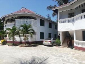 ディアニ・ビーチにあるPalm Beach Apartmentsの白い建物の前に停車する車