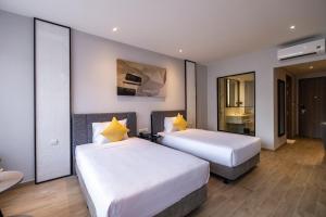 a hotel room with two beds and a mirror at Seava Ho Tram Beach Resort in Ho Coc