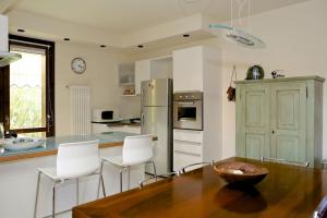 cocina con mesa de madera y sillas blancas en Villa con ampio giardino esterno e piscina condominiale, en Garda