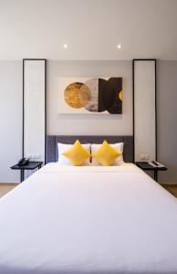 a bedroom with a large white bed with yellow pillows at Seava Ho Tram Beach Resort in Ho Coc