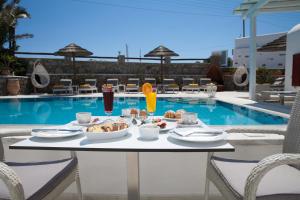 a table with food and drinks next to a pool at Domna Hotel in Mikonos
