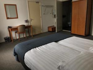 a hotel room with a large bed and a desk at Hotel Wilhelmina in Venlo +38 photos