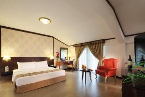 Village Hotel Albert Court by Far East Hospitality في سنغافورة: غرفة بالفندق سرير وكرسي احمر