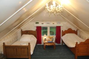 two beds in a attic bedroom with a chandelier at B&B Luttelhof, de goedkoopste in de regio ! in Luttelgeest