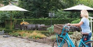 Eine Frau fährt ein blaues Fahrrad neben einem Regenschirm in der Unterkunft Hotel Internos in De Haan