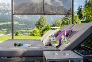 a bed and two wine glasses on a table at Hotel Der Bär in Ellmau