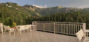 a balcony with a table and chairs and a mountain at Vatsalyam Home Stay in Shimla