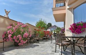 a patio with tables and chairs and pink flowers at Sirena Palace Family Hotel in Obzor