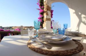a table with plates and forks and glasses on a table at Welcomely - Porto Cervo sul Mare in Porto Cervo