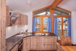 a kitchen with wooden cabinets and a large window at Ferienwohnungen Mayer inkl. Chiemgaukarte in Ruhpolding