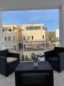 卡拉隆加的住宿－Apartamentos Torres Cardona (Playa)，阳台配有两把椅子和一张桌子,公寓大楼