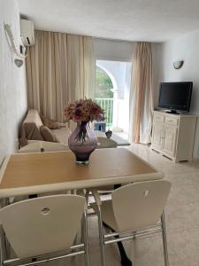 a living room with a table with a vase of flowers on it at Apartamentos Torres Cardona (Playa) in Cala Llonga