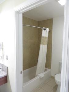 a bathroom with a bath tub and a toilet at National Inn Garden Grove in Anaheim