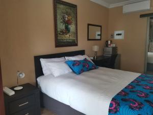 a bedroom with a large bed with a blue pillow at Aquila Guest House in Pretoria