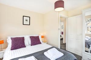 a bedroom with a large white bed with purple pillows at The Harrogate Penthouse in Harrogate