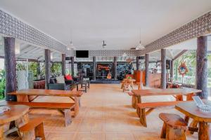a restaurant with wooden tables and benches and a fireplace at RedDoorz Plus near Tapal Kuda Cugenang Cianjur in Cianjur