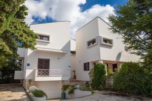 a white house with trees in front of it at House Emilija in Novalja