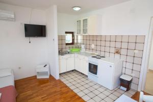 a small white kitchen with a sink and a stove at House Emilija in Novalja