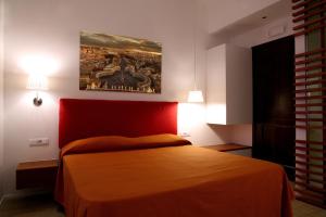 ローマにあるWhy Not Roma Suiteの赤いベッドと壁に絵画が飾られたベッドルーム1室