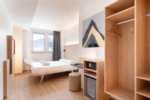 ein weißes Zimmer mit einem Bett und einem Tisch in der Unterkunft B&B Hotel Bolzano in Bozen