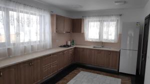 a kitchen with wooden cabinets and a refrigerator and windows at Pensiunea Simona in Rodna