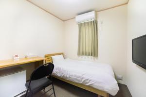 a room with a bed and a desk and a television at Tabist Hotel Daimu Minami-Souma in Minamisouma