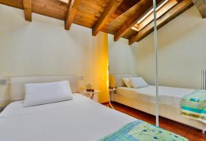 2 łóżka w pokoju z drewnianym sufitem w obiekcie UR-NEST Beverara w Bolonii