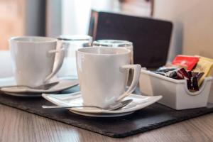 two white cups and saucers on a table at Hotel Cannaregio 2357 in Venice