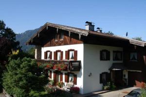a large white house with flowers on the balcony at Ferienwohnungen Praxenthaler inkl. Chiemgaukarte in Ruhpolding