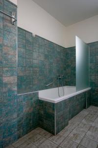 a bathroom with a tub and green tiled walls at Krinos Suites Andros in Andros