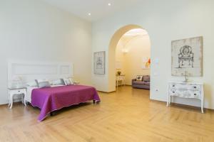 a bedroom with a bed with a purple blanket at La Gatta Cenerentola Rooms in Naples