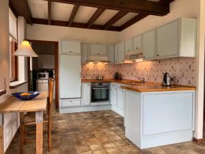 a kitchen with white cabinets and a wooden table at Koningshof in Schoorl
