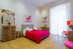 1 dormitorio con cama roja y vestidor en La Gatta Cenerentola Rooms en Nápoles