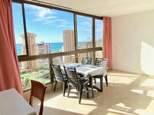 a dining room with a table and chairs and a large window at Los Gemelos 2- Aloturin Benidorm in Benidorm