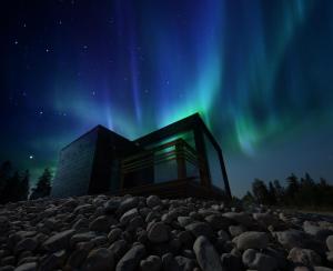 Una casa sotto l'aurora boreale nel cielo di Ukkohalla Sky Cabin Glass Suite a Hyrynsalmi