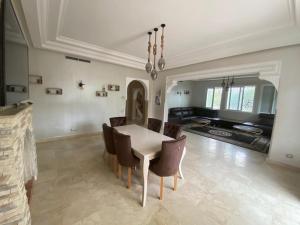 villa 31 de luxe avec Piscine hot gamme في طنجة: غرفة طعام مع طاولة وكراسي